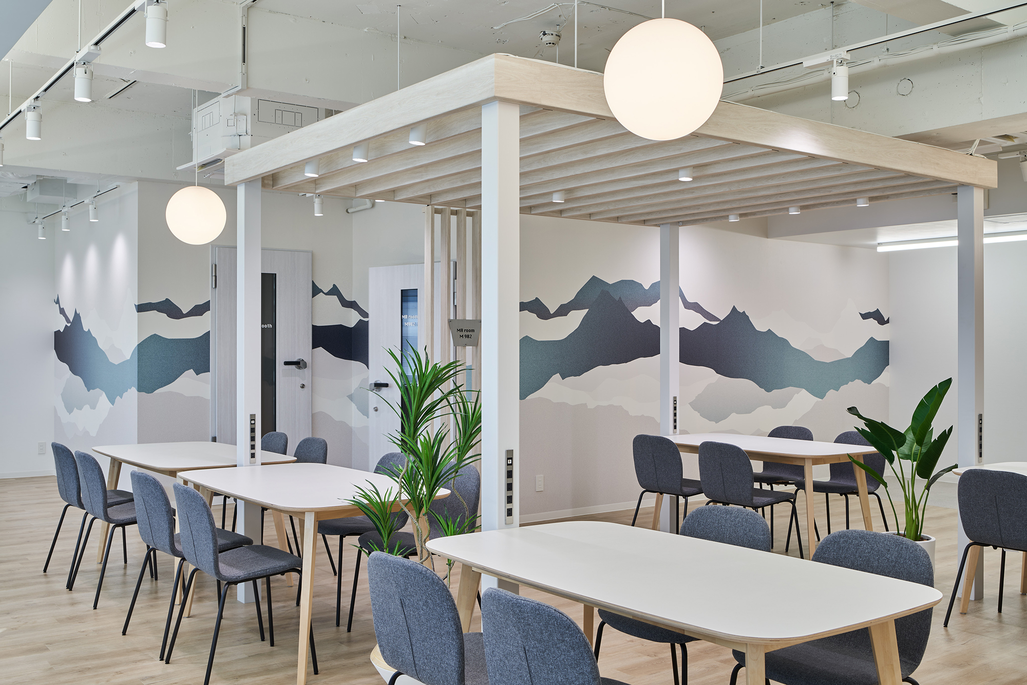 港区のオフィスのネイビーと白地の木の調和が美しいコミュニケーションスペースに、空間の色調とマッチした山並みを感じるデザインを展開。