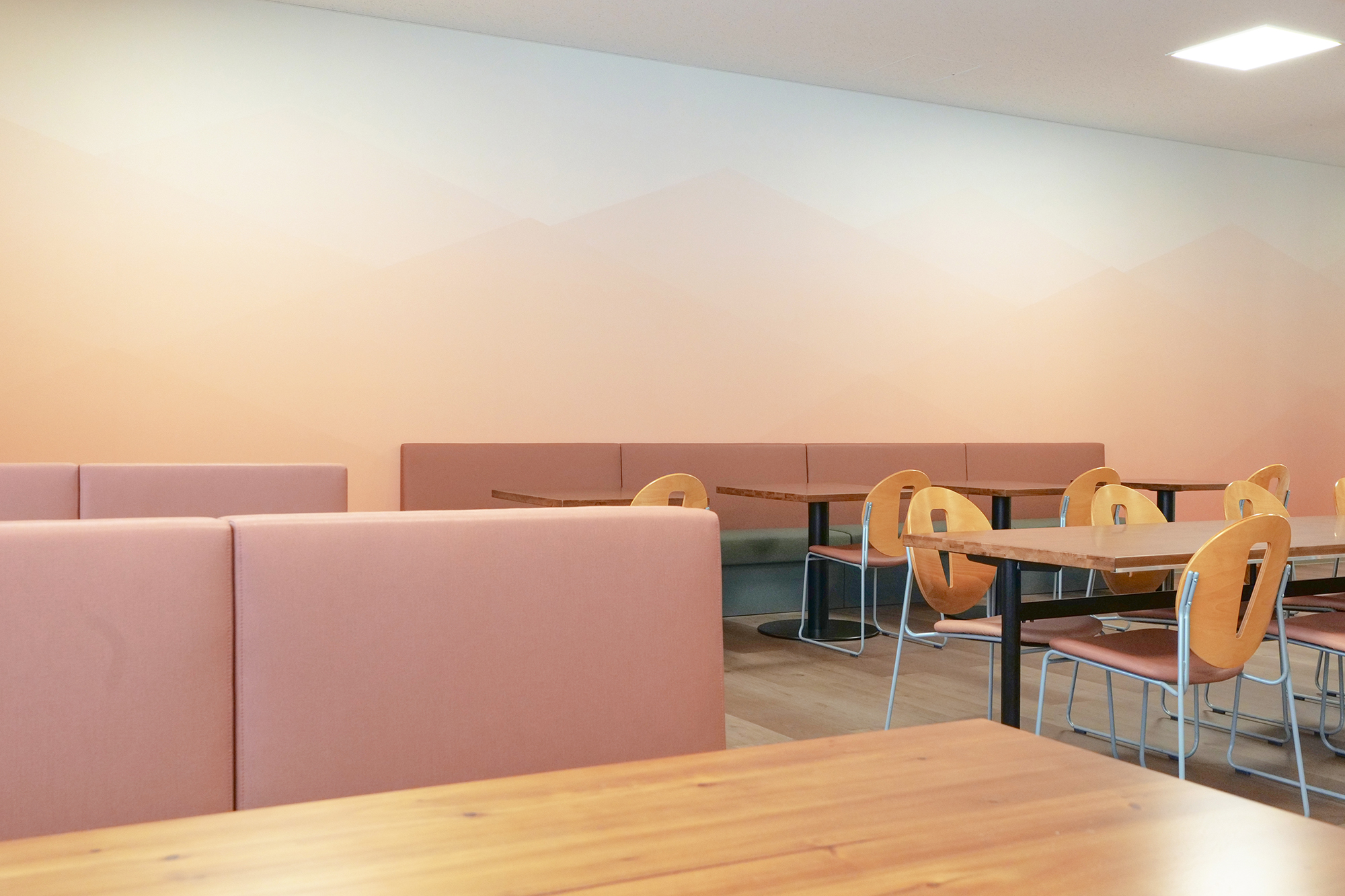 静岡県湖西市のオフィス・フリースペースにてチェアやソファの座面カラーに合わせたピンクのグラデーション壁紙を施工