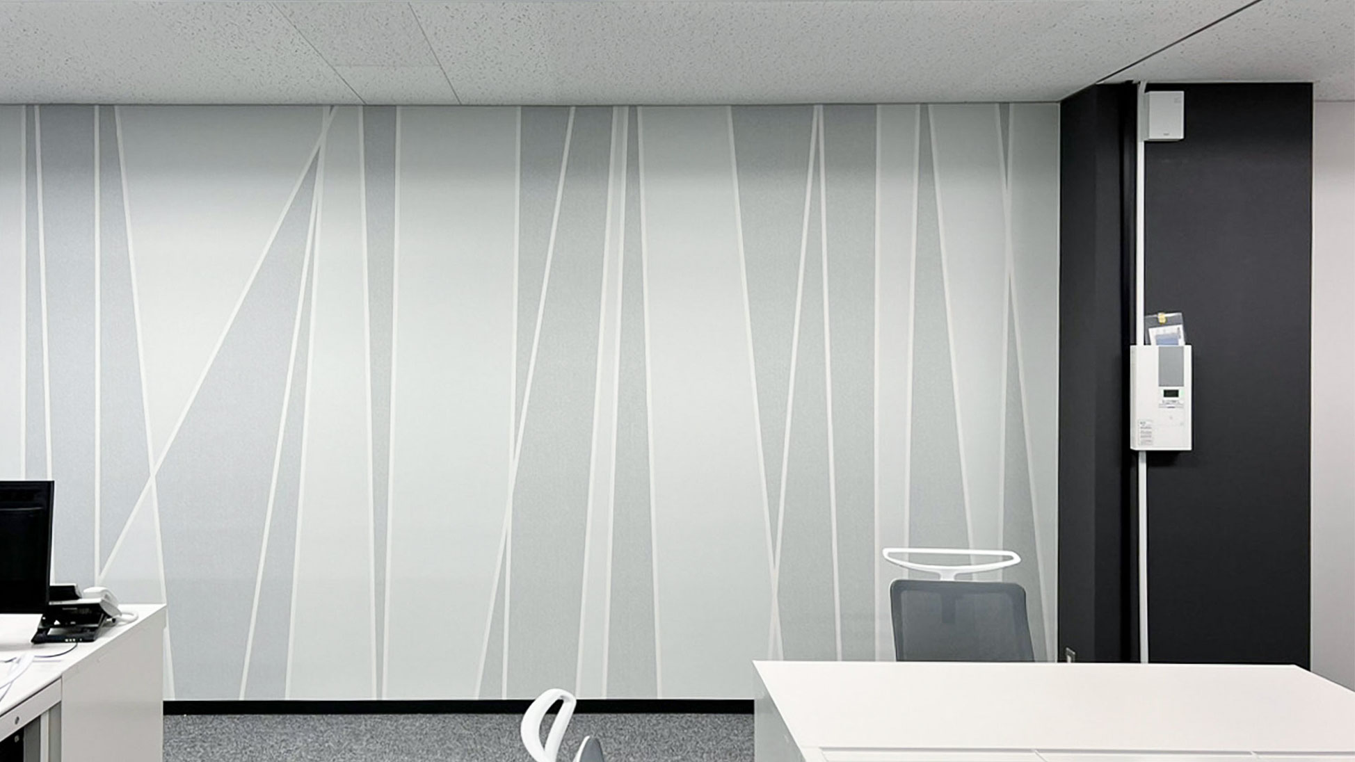 東京都のオフィスにて、ランダムな動きのあるモノトーンのラインで構成されたデザインを壁面へ施工