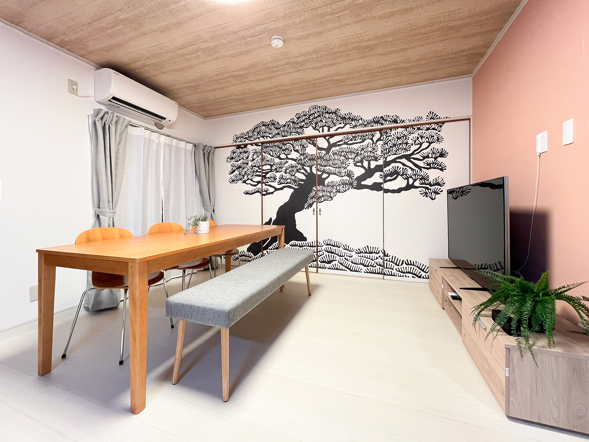 東京都墨田区の民泊施設内、リビングと寝室を隔てる建具へと展開。和の印象を引き立てる黒松がダイナミックに配された。